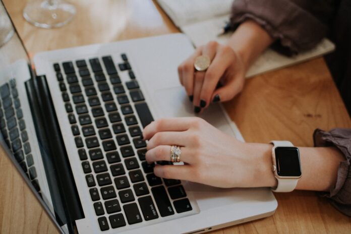 Writer using a laptop and notebook for AI-assisted writing